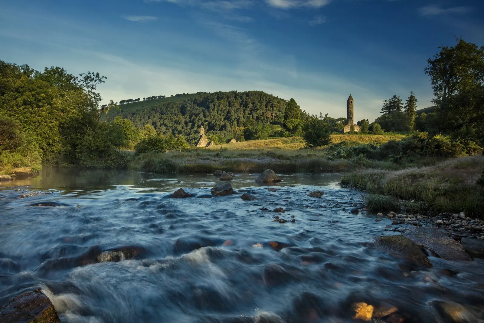 The round tower at Glendalough above the river running through the valley