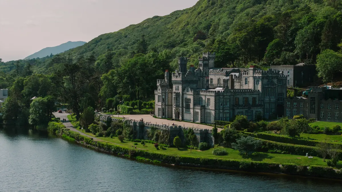 Kylemore Abbey overlooking a still lake beneath green hills